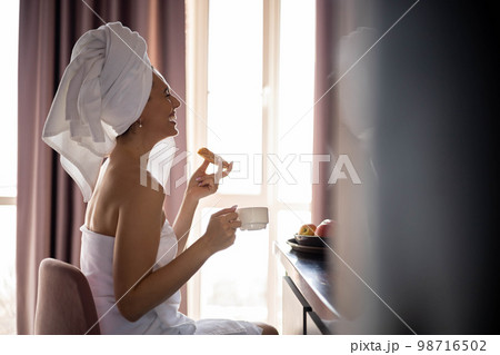 Relax woman in white towel sitting on bar counter breakfast at luxury home hotel apartment back view Relax woman in white towel sitting on bar counter breakfast at luxury home hotel apartment back view 98716502