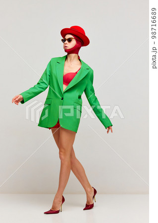 Creative fashion portrait of stylish young girl in red hat and shorts dancing isolated over grey background. Concept of high fashion, art photography, style, queer, beauty Creative fashion portrait of stylish young girl in red hat and shorts dancing isolated over grey background. Concept of high fashion, art photography, style, queer, beauty 98716689