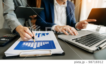 Business coworkers colleagues working together, have a discussion and using tablet and laptop computer at office with financial document on desk. 98716912