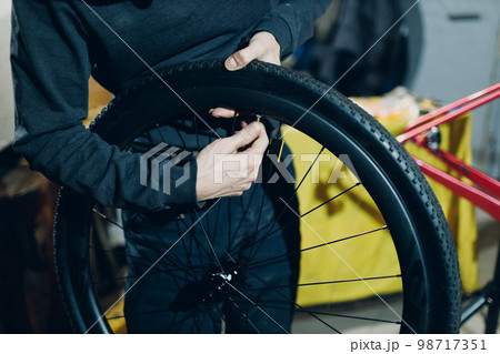 Mechanic repairman assembling wheel nipple rim custom bicycle in workshop Mechanic repairman assembling wheel nipple rim custom bicycle in workshop 98717351