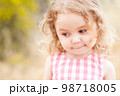 Close up portrait of cute baby girl 2-3 year old posing outdoors. Cute child. Looking away. Childhood. 98718005
