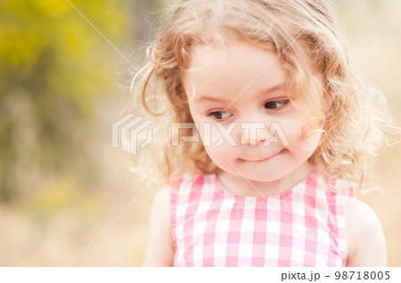 Close up portrait of cute baby girl 2-3 year old posing outdoors. Cute child. Looking away. Childhood. 98718005