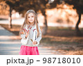 Smiling baby girl 4-5 year old posing outdoors over nature background. Looking at camera. Childhood. 98718010
