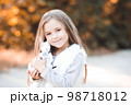 Cute smiling baby girl 4-5 year old holding toy rabbit outdoors over nature background. Looking at camera. Childhood. 98718012