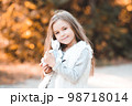 Pretty child girl 5-6 year old holding cute toy rabbit outdoors. Looking at camera. Childhood. 98718014