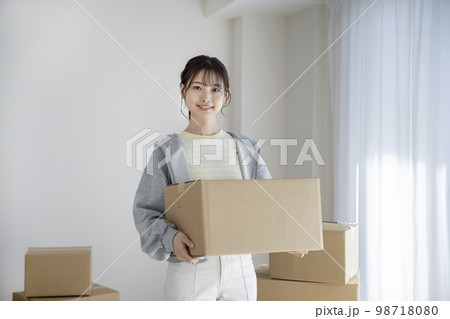 段ボール箱を持ったカメラ目線の若い女性　引越し　イメージ 98718080