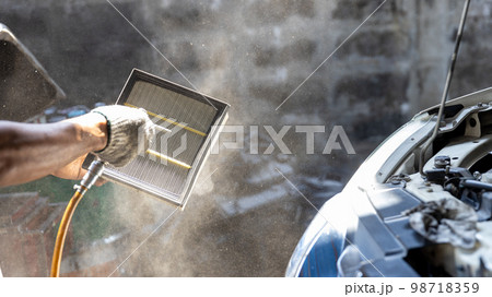 Mechanic cleaning dirty car air filter with air blow gun. Mechanic cleaning dirty car air filter with air blow gun. 98718359