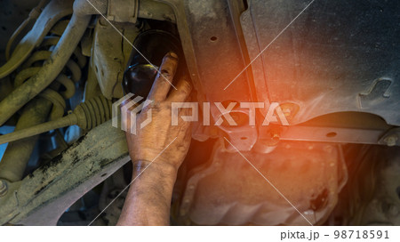 Technician change car oil filter under car. 98718591