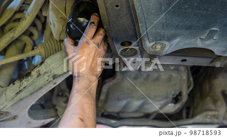 Technician change car oil filter under car. Technician change car oil filter under car. 98718593