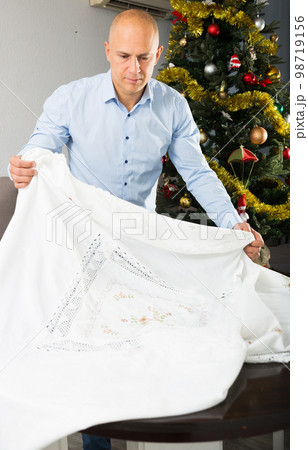 Man spreading tablecloth on table 98719156