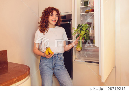 Ginger girl unpacking and putting food to the fridge 98719215