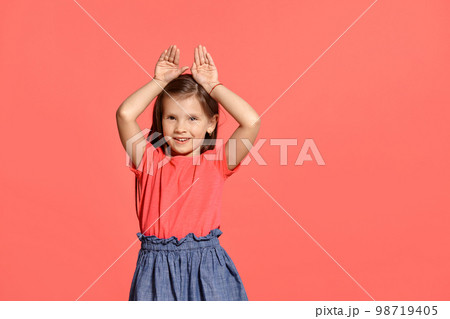 Close-up studio shot of beautiful brunette little girl posing against a blue background. Close-up studio shot of beautiful brunette little girl posing against a blue background. 98719405