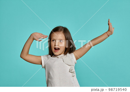 Close-up studio shot of beautiful brunette little girl posing against a blue background. 98719540