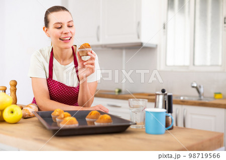 Positive housewife with just baked hot cupcakes 98719566
