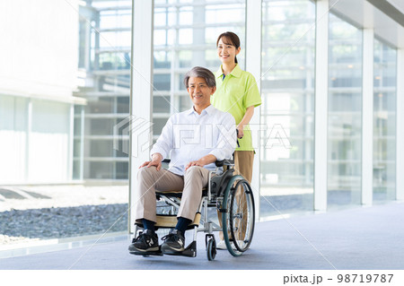 車椅子のシニアの男性と介護福祉士 98719787