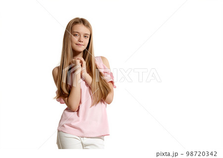 Studio portrait of a beautiful girl blonde teenager in a pink t-shirt posing isolated on white background. Studio portrait of a beautiful girl blonde teenager in a pink t-shirt posing isolated on white background. 98720342