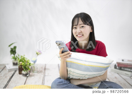 リビングでスマホを見る若い女性 98720566