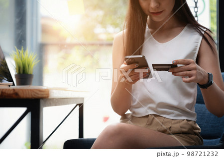 Woman enjoy with online shopping application and looking at credit card for fill number to payment. 98721232