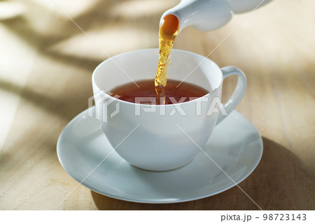 爽やかな陽ざしを受けて紅茶を注ぐ 98723143