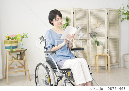 家で読書する車椅子に乗った障がい者女性 家で読書する車椅子に乗った障がい者女性 98724463