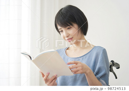 家で読書する車椅子に乗った障がい者女性 98724513