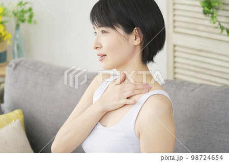 家で胸元のマッサージをする女性 98724654