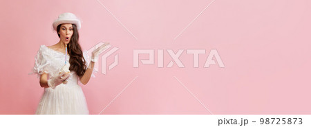 Portrait of beautiful lady in white vintage dress posing with birthday cake over pink background. Concept of 19th century, fashion, comparison of eras Portrait of beautiful lady in white vintage dress posing with birthday cake over pink background. Concept of 19th century, fashion, comparison of eras 98725873