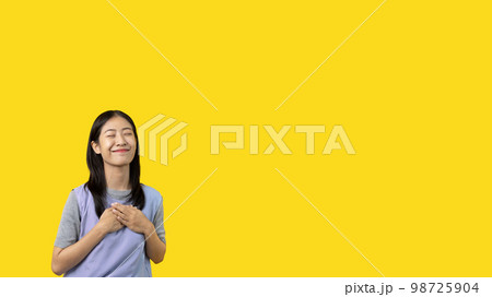 Asian woman smiling happily isolated on yellow background, Woman loves and rejoices herself, Contented, Pure love, Love myself, Proud of yourself, Self-made happiness, Optimism. 98725904