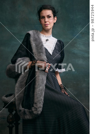 Proud woman. Beautiful woman in image of Anna Karenina posing in retro dress over vintage dark green background. Concept of literature character, history Proud woman. Beautiful woman in image of Anna Karenina posing in retro dress over vintage dark green background. Concept of literature character, history 98725944