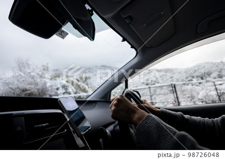 雪が積もっている道路を運転している自動車の運転席と外の冬景色 98726048