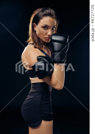Athletic woman in boxing gloves is practicing karate in studio. 98727726