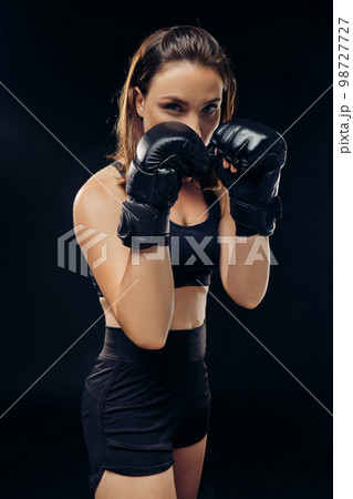 Athletic woman in boxing gloves is practicing karate in studio. Athletic woman in boxing gloves is practicing karate in studio. 98727727