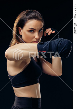 Athletic woman in boxing mittens is practicing karate in studio. 98727729