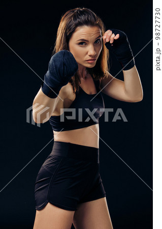 Athletic woman in boxing mittens is practicing karate in studio. 98727730