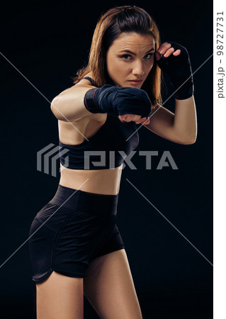 Athletic woman in boxing mittens is practicing karate in studio. 98727731