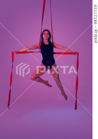 Beautiful girl in a black swimsuit is performing an acrobatic elements in studio. 98727739