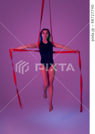 Beautiful girl in a black swimsuit is performing an acrobatic elements in studio. 98727740