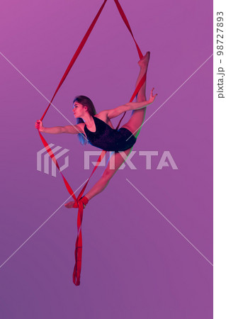 Beautiful girl in a black swimsuit is performing an acrobatic elements in studio. 98727893