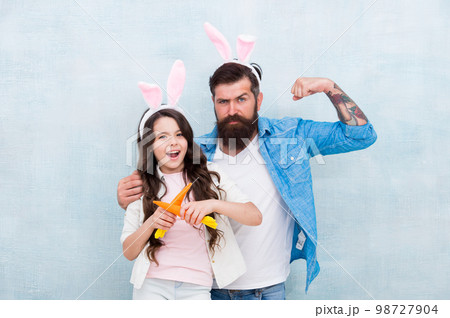 Funny team. Spring holiday. Celebrate easter. Easter food. Girl and dad bunny ears. Happy family wear bunny ears. Easter fun and happiness. Father and daughter play with carrots. Shopping grocery Funny team. Spring holiday. Celebrate easter. Easter food. Girl and dad bunny ears. Happy family wear bunny ears. Easter fun and happiness. Father and daughter play with carrots. Shopping grocery 98727904