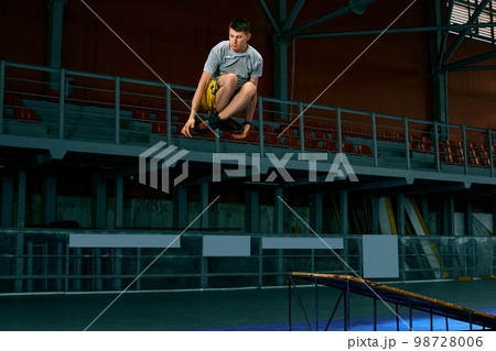Rollerblader jump high from big air ramp performing trick. Indoors skate park equipment. Rollerblader jump high from big air ramp performing trick. Indoors skate park equipment. 98728006