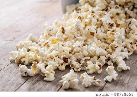 Salted popcorn scattered on wooden table Salted popcorn scattered on wooden table 98728655