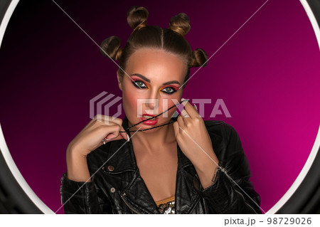 Portrait of a young sassy girl with blond hair in the studio on a pink background. Portrait of a young sassy girl with blond hair in the studio on a pink background. 98729026