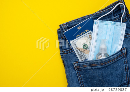 Pocket with jeans passport money and protective mask. Pandemic travel concept. Pocket with jeans passport money and protective mask. Pandemic travel concept. 98729027