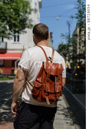 Orange leather oldfashioned backpack on a mans back 98729054