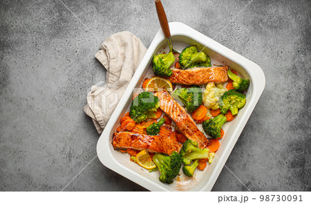 Top view of healthy baked fish salmon steaks, broccoli, cauliflower, carrot in casserole dish. Cooking a delicious low carb dinner, healthy nutrition concept 98730091
