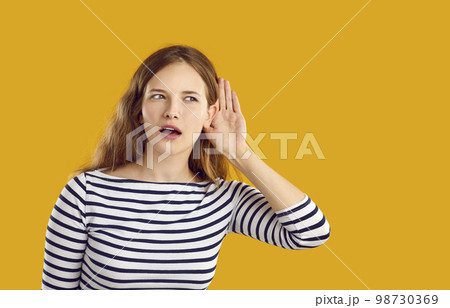 Curious young woman listening to gossip or eavesdropping on someone's conversation Curious young woman listening to gossip or eavesdropping on someone's conversation 98730369