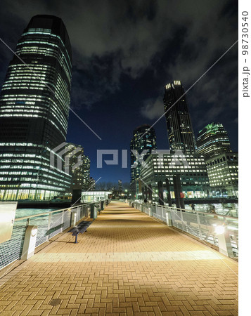 夜のオフィスビルと街頭に照らされる道 98730540