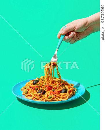 Eating spaghetti puttanesca, a vegan pasta dish, minimalist on a green background 98730560