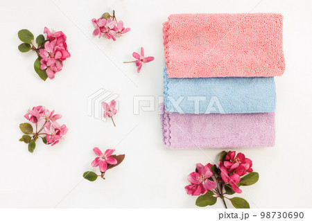 New folded microfiber cloth for cleaning on white with spring flowers background. Cleaning micro fabric towels for dusting and polishing. Domestic household cleaning service concept. Top view New folded microfiber cloth for cleaning on white with spring flowers background. Cleaning micro fabric towels for dusting and polishing. Domestic household cleaning service concept. Top view 98730690