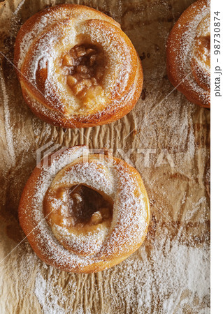 Freshly baked pastries with jam on baking paper decorated with sugar powder Freshly baked pastries with jam on baking paper decorated with sugar powder 98730874